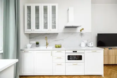 a white kitchen with white cabinets and a sink at Native Apartments Żuławskiego 8 in Kraków