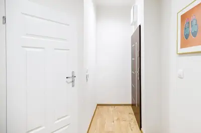 a hallway with white walls and a black door at Native Apartments Żuławskiego 8 in Kraków