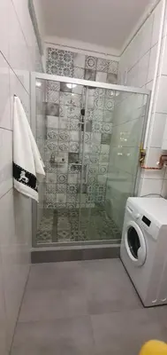 a shower in a bathroom with a washing machine at Apartament Orchidea in Kraków