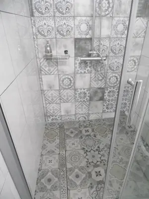a bathroom with a shower with a tiled floor at Apartament Orchidea in Kraków