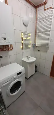 a bathroom with a washing machine and a sink at Apartament Orchidea in Kraków