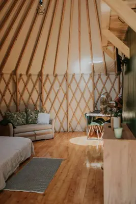 a room with a couch and a table in a yurt at Aloha Glamp - Całoroczny glamping nad rzeką z prywatną balią - Stok narciarski, góry, lasy, sauna in Zagórnik