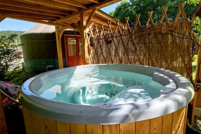a hot tub in a backyard with a wooden fence at Aloha Glamp - Całoroczny glamping nad rzeką z prywatną balią - Stok narciarski, góry, lasy, sauna in Zagórnik