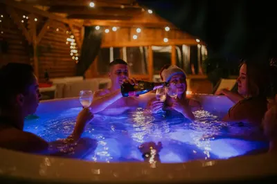 a group of people in a hot tub drinking at Aloha Glamp - Całoroczny glamping nad rzeką z prywatną balią - Stok narciarski, góry, lasy, sauna in Zagórnik
