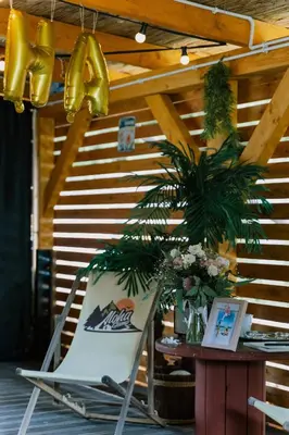 a chair sitting next to a table with a plant at Aloha Glamp - Całoroczny glamping nad rzeką z prywatną balią - Stok narciarski, góry, lasy, sauna in Zagórnik