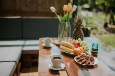 a table topped with plates of fruit and cups of coffee at Aloha Glamp - Całoroczny glamping nad rzeką z prywatną balią - Stok narciarski, góry, lasy, sauna in Zagórnik