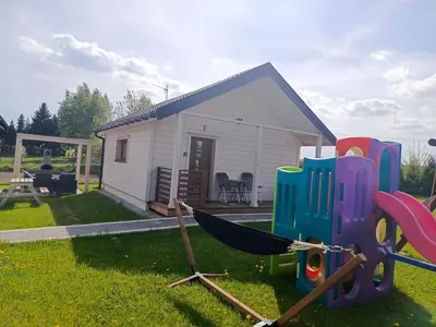a small house with a hammock in the yard at Domki Magnolia Noclegi & SPA Zator in Zator