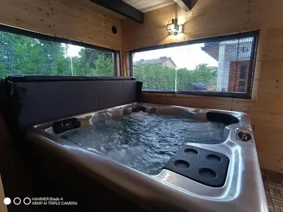 a hot tub in a room with two windows at Domki Magnolia Noclegi & SPA Zator in Zator