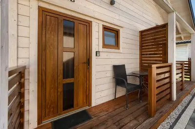 a wooden door on a porch with a table and a chair at Domki Magnolia Noclegi & SPA Zator in Zator