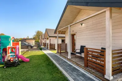 a backyard with a house and a yard with a playground at Domki Magnolia Noclegi & SPA Zator in Zator