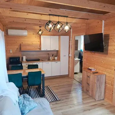 a kitchen and living room with a table and a television at Domki Magnolia Noclegi & SPA Zator in Zator