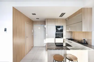 a kitchen with wooden cabinets and a counter with stools at Apartamenty Platinex in Kraków