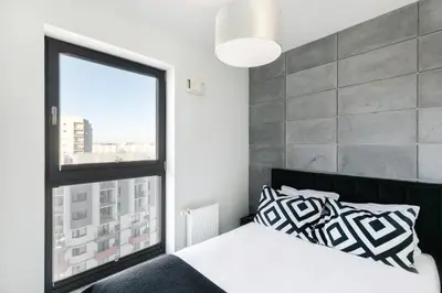 a bedroom with a bed and a large window at Apartamenty Platinex in Kraków