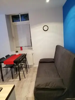 a living room with a couch and a table and a clock at Apartament Galicja Plus in Chrzanów