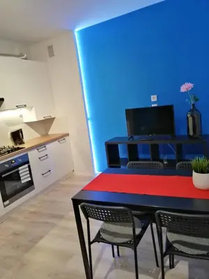 a kitchen with a table with chairs and a blue wall at Apartament Galicja Plus in Chrzanów