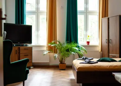 a bedroom with a bed and a tv and windows at Bailey Apartment in Kraków