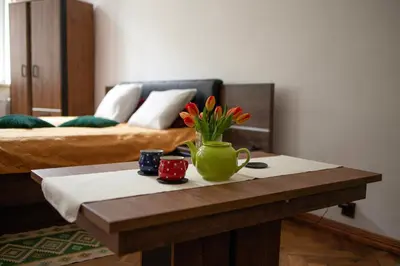 a coffee table with a green vase with flowers on it at Bailey Apartment in Kraków
