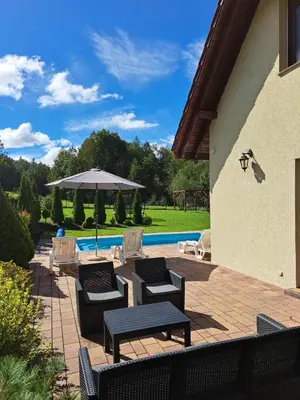 a patio with chairs and an umbrella and a pool at Dom na polanie in Brzeźnica