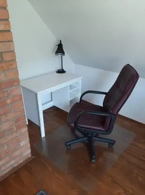 a desk and a chair next to a white desk with a lamp at Dom na polanie in Brzeźnica
