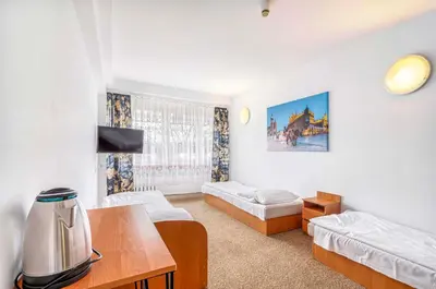a living room with two beds and a table at Hotel Biała Gwiazda in Kraków
