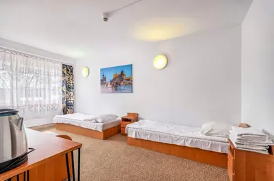 a bedroom with two beds and a table and a tv at Hotel Biała Gwiazda in Kraków