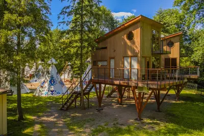 a tree house on a platform in a yard at Apartamenty wśród drzew River Park Zator SPA JACUZZI in Zator