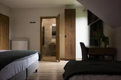 a bedroom with two beds and a bathroom with a sink at Barwald Hills - jacuzzi i piękny widok na Babią Górę i Beskidy in Wadowice