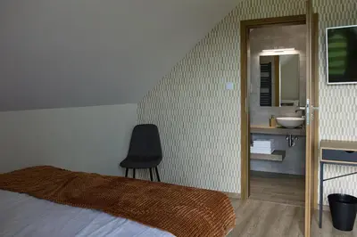 a bedroom with a bed and a chair and a sink at Barwald Hills - jacuzzi i piękny widok na Babią Górę i Beskidy in Wadowice
