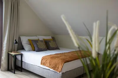 a bedroom with a bed with pillows and a plant at Barwald Hills - jacuzzi i piękny widok na Babią Górę i Beskidy in Wadowice