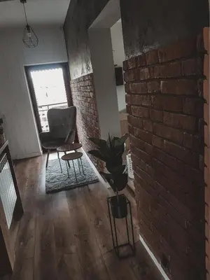 a living room with a brick wall and a chair at Jaszczurowa Apartament in Jaszczurowa