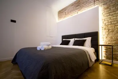 a bedroom with a large bed with a brick wall at Wanderlust Apartments in Kraków