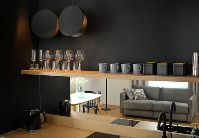 a living room with glasses on a shelf with a couch at Wanderlust Apartments in Kraków
