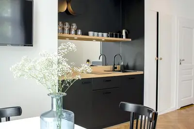 a kitchen with black cabinets and a vase with flowers at Wanderlust Apartments in Kraków