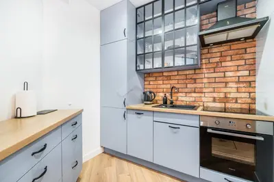 a kitchen with white cabinets and a brick wall at Kraków City Center Luxury Apartment in Kraków