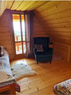 a room with a chair in a log cabin at Widokowa Chata in Obidowa