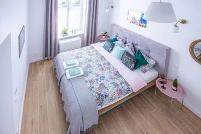 a bedroom with a large bed with blue and green pillows at Apartament Ex Libris in Kraków