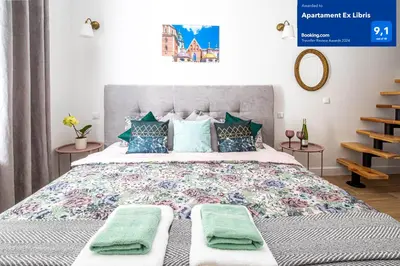 a bedroom with a large bed with green towels on it at Apartament Ex Libris in Kraków