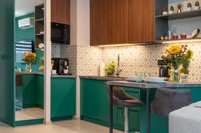 a kitchen with green cabinets and a table at WawelSee Apartments in Kraków