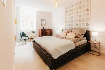 a bedroom with a large bed and a chair at DeLux Apartament OldTown Kochanowskiego 30 Kraków in Kraków