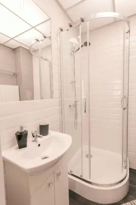a white bathroom with a shower and a sink at DeLux Apartament OldTown Kochanowskiego 30 Kraków in Kraków