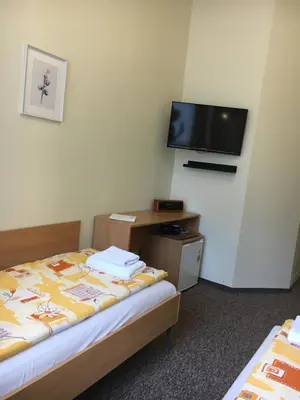 a room with two beds and a tv on the wall at Piast Hotele Studenckie in Kraków