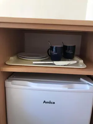 two cups and plates on a shelf above a dishwasher at Piast Hotele Studenckie in Kraków