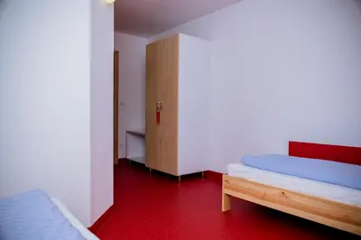 a room with two beds and a cabinet in it at Międzynarodowy Dom Spotkań Młodzieży w Oświęcimiu in Oświęcim