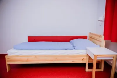 a bed with a wooden frame and a table at Międzynarodowy Dom Spotkań Młodzieży w Oświęcimiu in Oświęcim