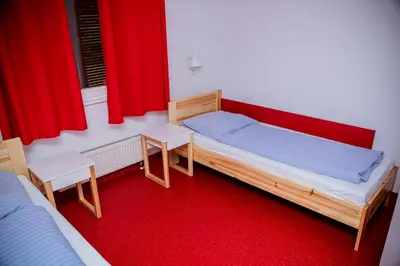 a bedroom with two beds and red curtains at Międzynarodowy Dom Spotkań Młodzieży w Oświęcimiu in Oświęcim