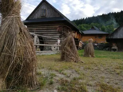 a log cabin with hay stacks in front of it at Domki Karczma Zbójnicka in Wiśniowa