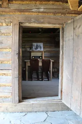 an entrance to a wooden house with a table and chairs at Domki Karczma Zbójnicka in Wiśniowa