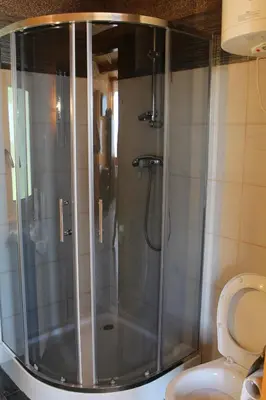 a shower stall in a bathroom with a toilet at Domki Karczma Zbójnicka in Wiśniowa