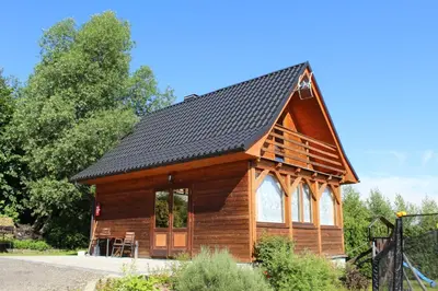 a log cabin with a black roof at Domki Karczma Zbójnicka in Wiśniowa