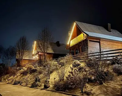 a building with snow on the ground in front of it at Domki Karczma Zbójnicka in Wiśniowa